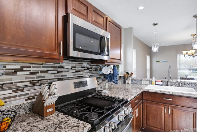 kitchen with sink, stainless steel appliances, an inviting chandelier, tasteful backsplash, and pendant lighting