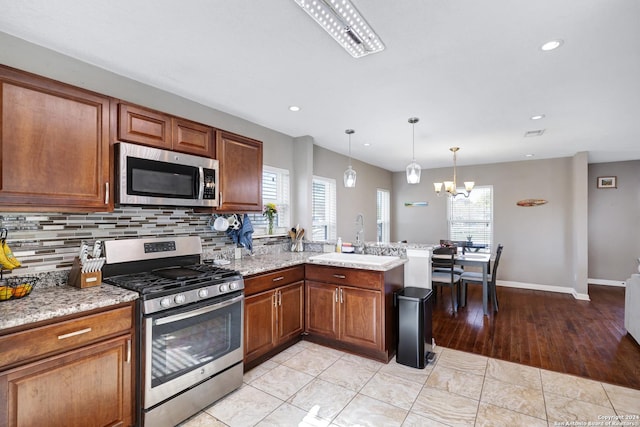 kitchen with stainless steel appliances, a notable chandelier, a healthy amount of sunlight, and light hardwood / wood-style floors