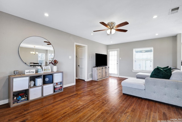 living room featuring ceiling fan with notable chandelier and dark hardwood / wood-style floors