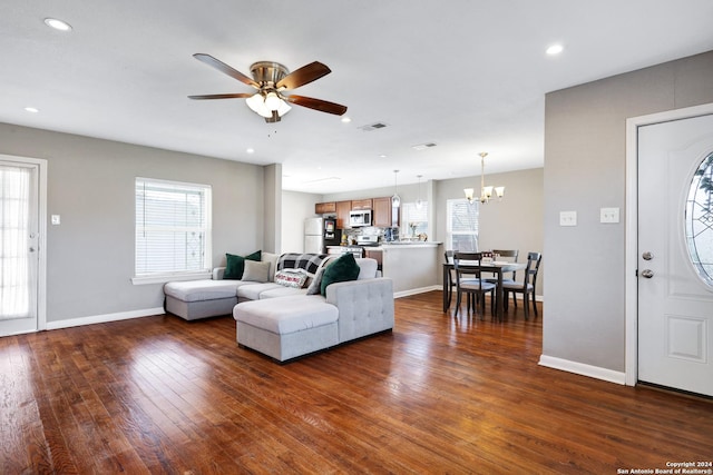 living room featuring a wealth of natural light, dark wood-type flooring, and ceiling fan with notable chandelier