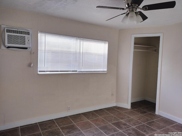 unfurnished bedroom featuring a textured ceiling, ceiling fan, a closet, and a wall mounted air conditioner