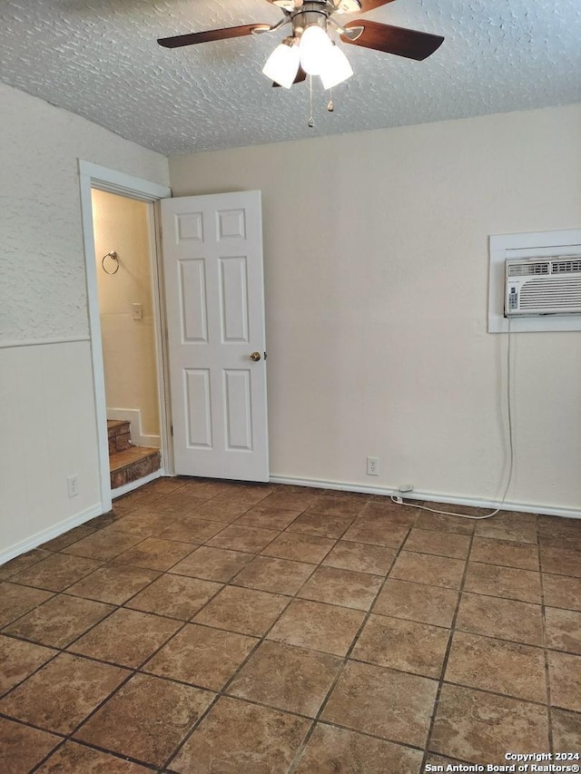 empty room featuring a textured ceiling, a wall unit AC, and ceiling fan