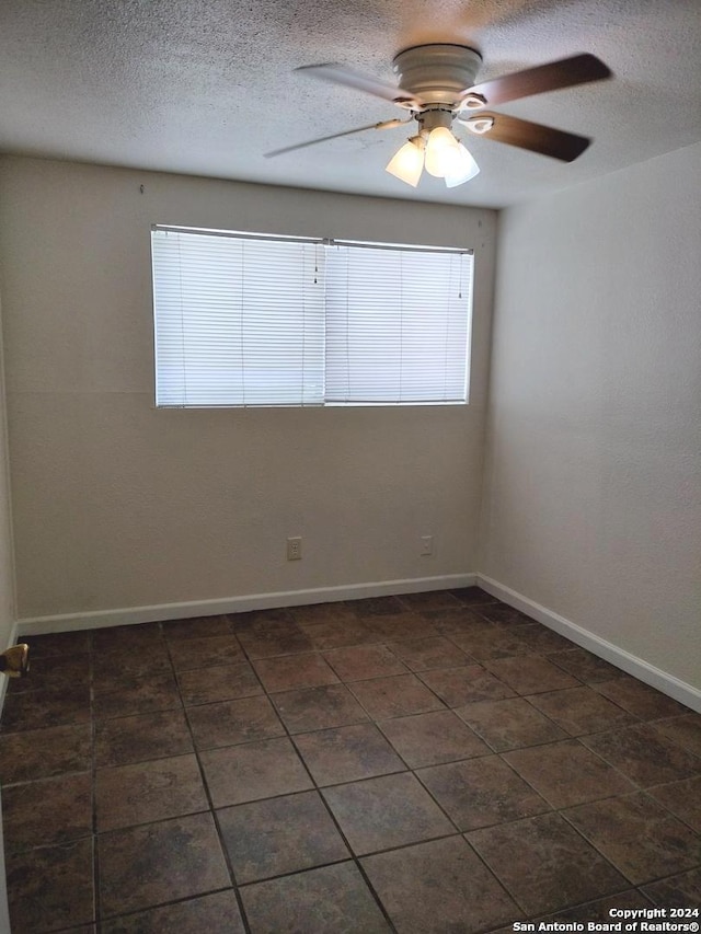 unfurnished room with ceiling fan and a textured ceiling