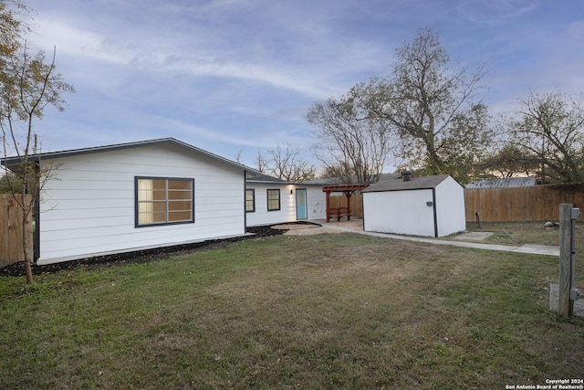 rear view of house featuring a storage shed and a yard