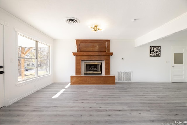 unfurnished living room featuring a large fireplace, light hardwood / wood-style flooring, and crown molding