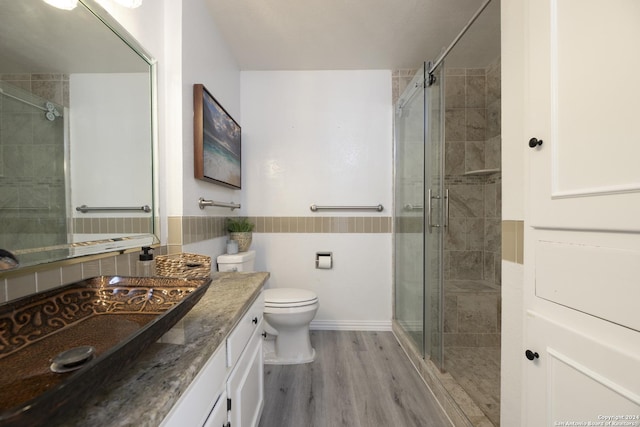 bathroom with an enclosed shower, vanity, toilet, and wood-type flooring