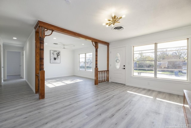 foyer with ornamental molding, ceiling fan with notable chandelier, and light wood-type flooring