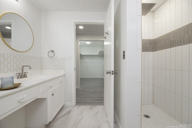 bathroom with tiled shower, hardwood / wood-style floors, and vanity