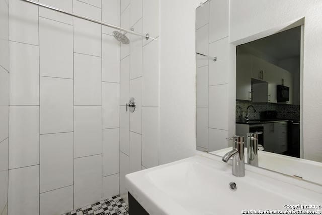 bathroom featuring a tile shower, tasteful backsplash, and vanity