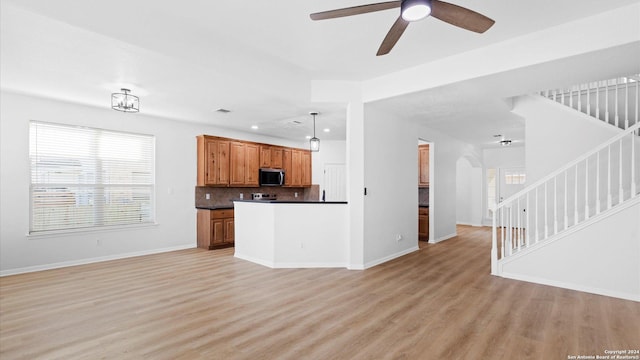 kitchen featuring appliances with stainless steel finishes, backsplash, ceiling fan, pendant lighting, and light hardwood / wood-style floors