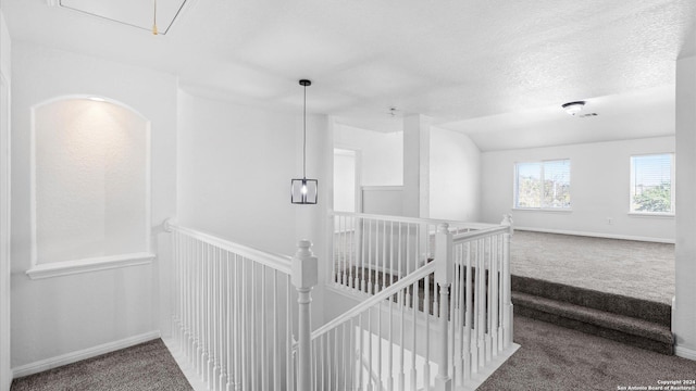 corridor with carpet, lofted ceiling, and a textured ceiling