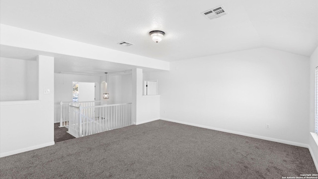 spare room featuring dark colored carpet and lofted ceiling