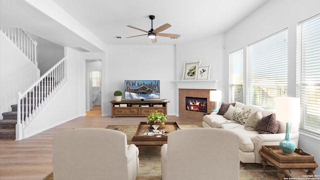 living room with a fireplace, light hardwood / wood-style flooring, and ceiling fan