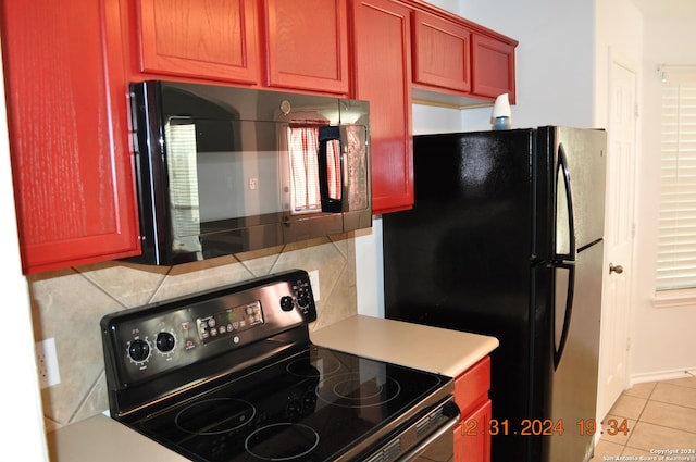 kitchen featuring backsplash, light tile patterned floors, and black appliances