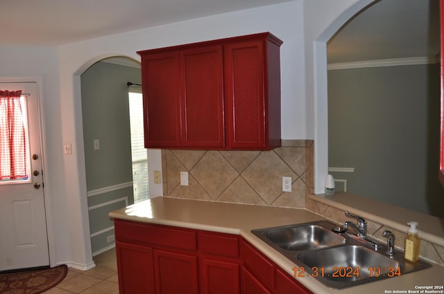 kitchen featuring backsplash, sink, light tile patterned floors, and ornamental molding