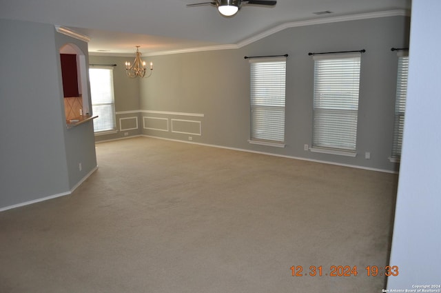 carpeted spare room with ceiling fan with notable chandelier, ornamental molding, and vaulted ceiling