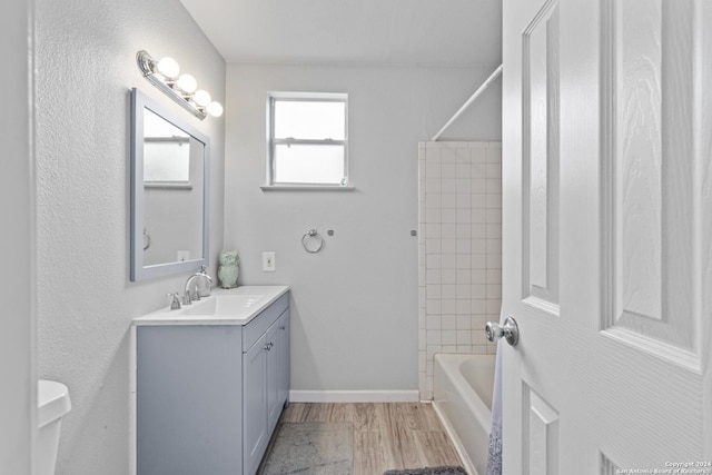 bathroom featuring vanity, wood-type flooring, and tiled shower / bath