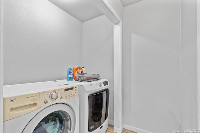 clothes washing area with washing machine and dryer and light hardwood / wood-style floors