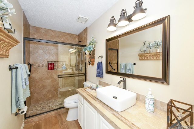 bathroom with vanity, hardwood / wood-style flooring, toilet, a textured ceiling, and walk in shower