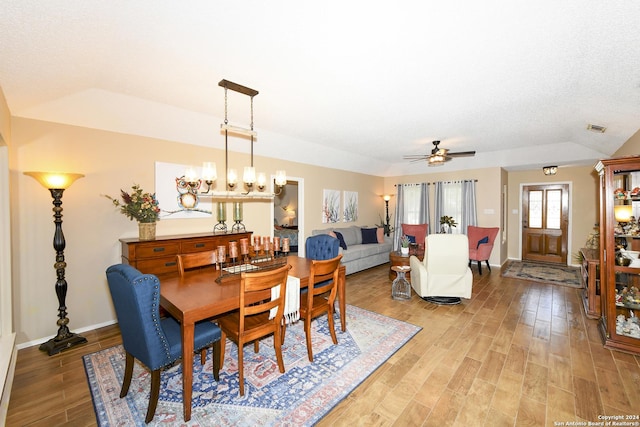 dining room with a textured ceiling, ceiling fan with notable chandelier, and light wood-type flooring