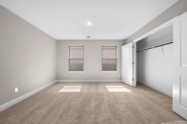 unfurnished bedroom with light carpet and a closet