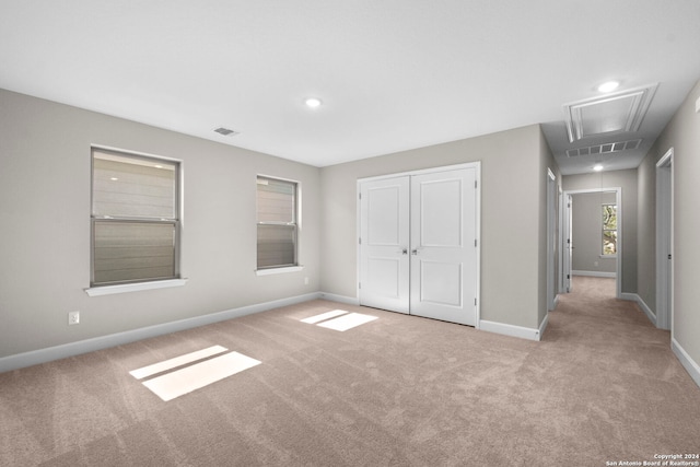 unfurnished bedroom featuring light colored carpet and a closet