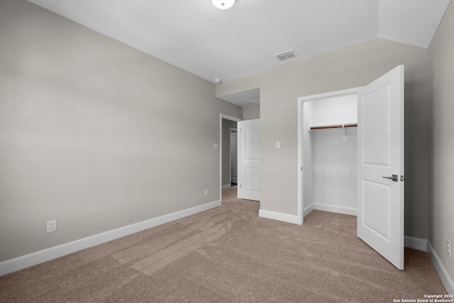 unfurnished bedroom featuring light colored carpet, a closet, and lofted ceiling