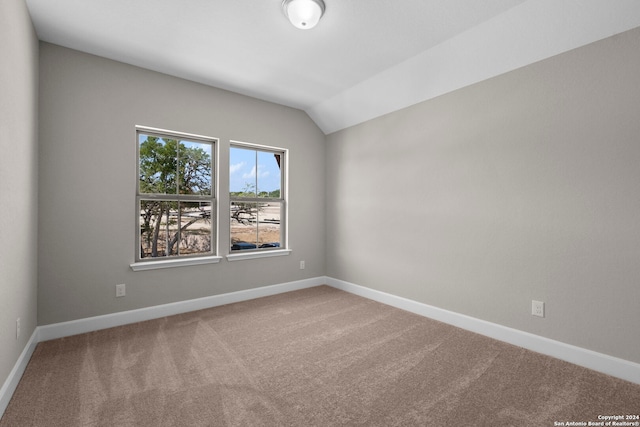 carpeted empty room with vaulted ceiling