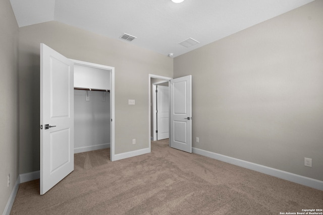 unfurnished bedroom with vaulted ceiling, light carpet, and a closet