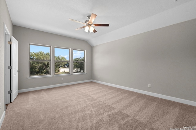 carpeted spare room with ceiling fan and vaulted ceiling