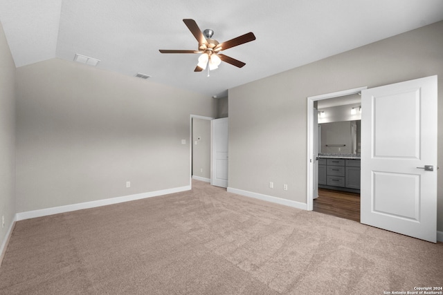 unfurnished bedroom featuring connected bathroom, ceiling fan, light carpet, and lofted ceiling