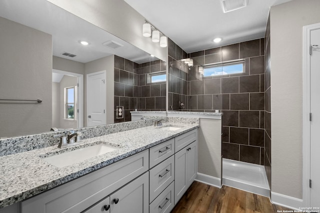 bathroom with hardwood / wood-style floors, vanity, and tiled shower