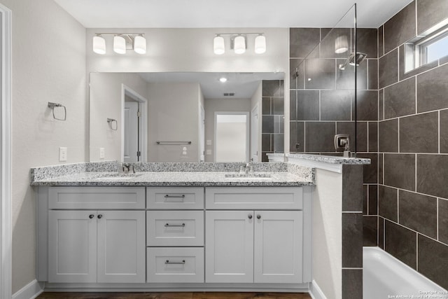 bathroom with a tile shower and vanity