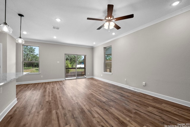 unfurnished living room featuring dark wood-type flooring, crown molding, ceiling fan, and a healthy amount of sunlight