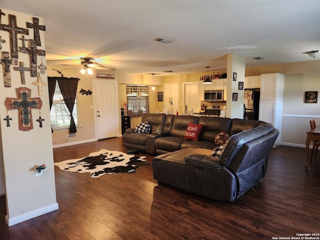 living room featuring ceiling fan, dark wood-type flooring, and a textured ceiling