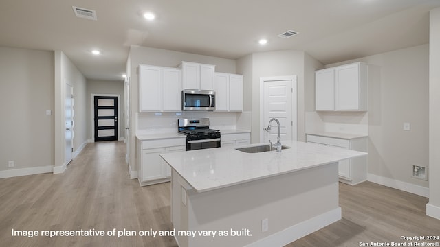 kitchen featuring white cabinets, an island with sink, stainless steel appliances, and sink