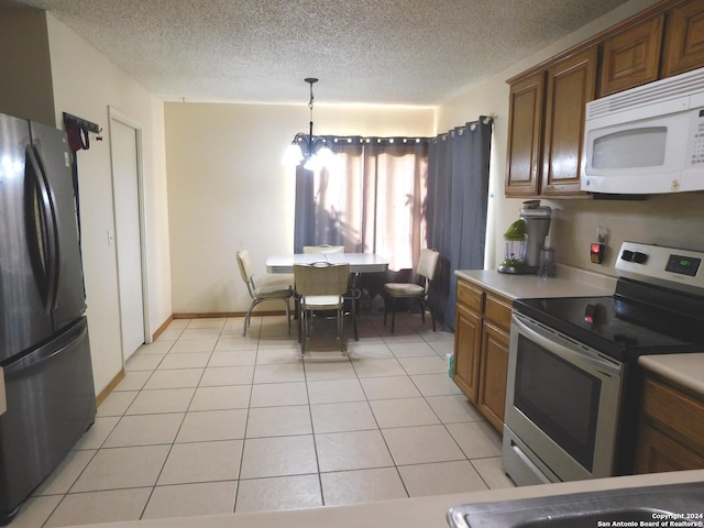 kitchen with pendant lighting, a textured ceiling, stainless steel range with electric stovetop, fridge, and light tile patterned floors