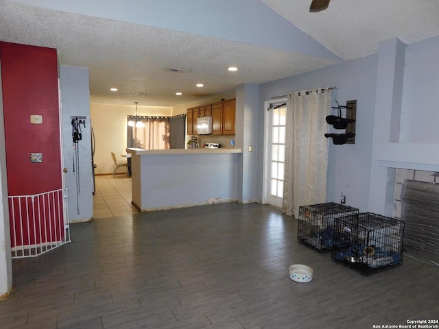 living room featuring hardwood / wood-style floors, ceiling fan with notable chandelier, and a textured ceiling