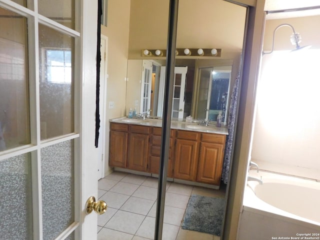 bathroom with a bath, vanity, and tile patterned floors