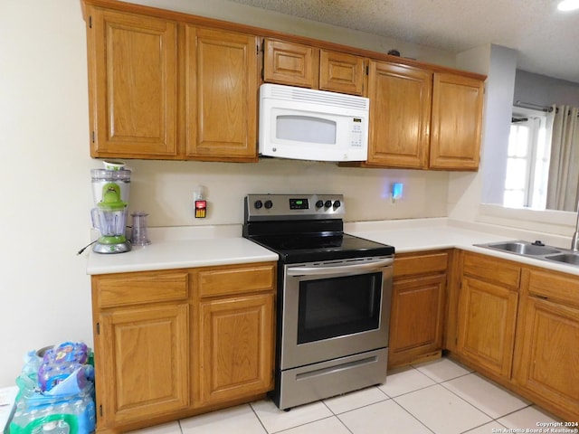 kitchen featuring electric range, light tile patterned floors, sink, and a textured ceiling