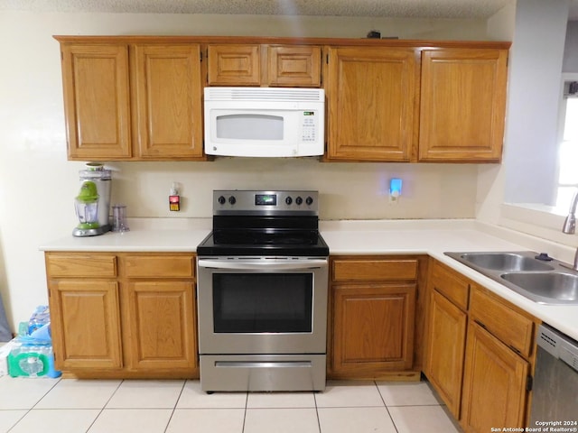 kitchen featuring a textured ceiling, sink, light tile patterned floors, and stainless steel appliances