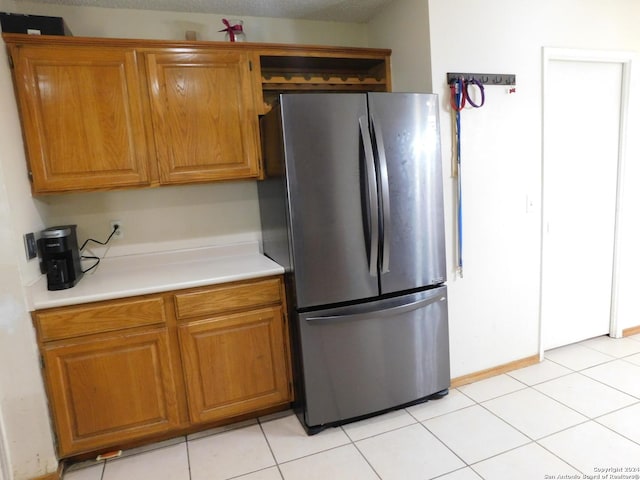 kitchen with stainless steel fridge, a textured ceiling, and light tile patterned floors