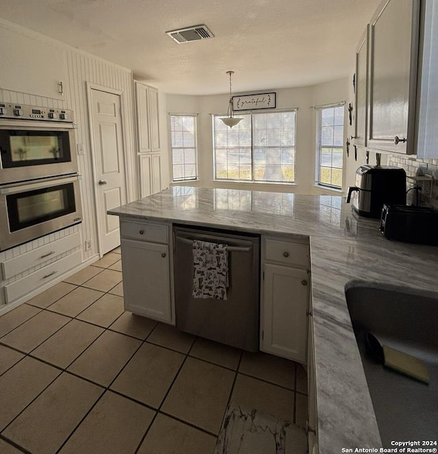 kitchen with white cabinets, a healthy amount of sunlight, decorative light fixtures, and appliances with stainless steel finishes