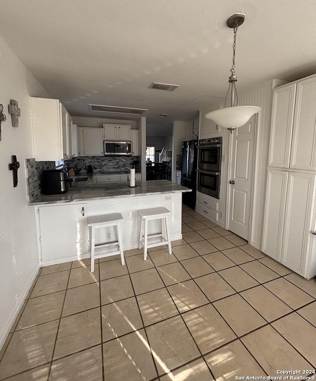 kitchen with white cabinetry, stainless steel appliances, kitchen peninsula, a breakfast bar area, and decorative backsplash