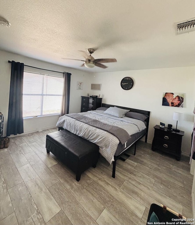 bedroom featuring a textured ceiling, light hardwood / wood-style flooring, and ceiling fan