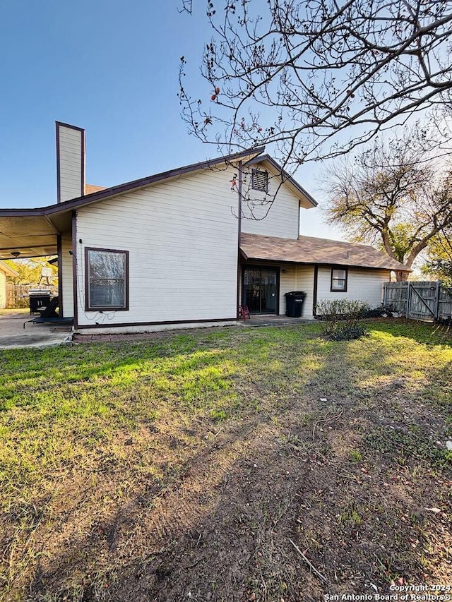 back of property featuring a carport and a lawn