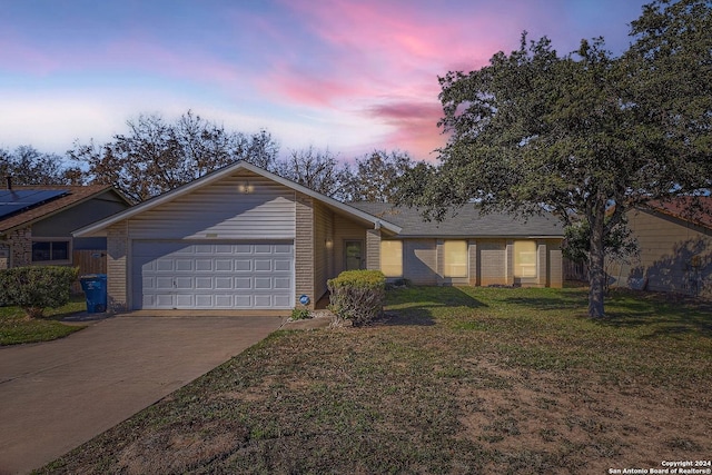 ranch-style house featuring a garage and a lawn