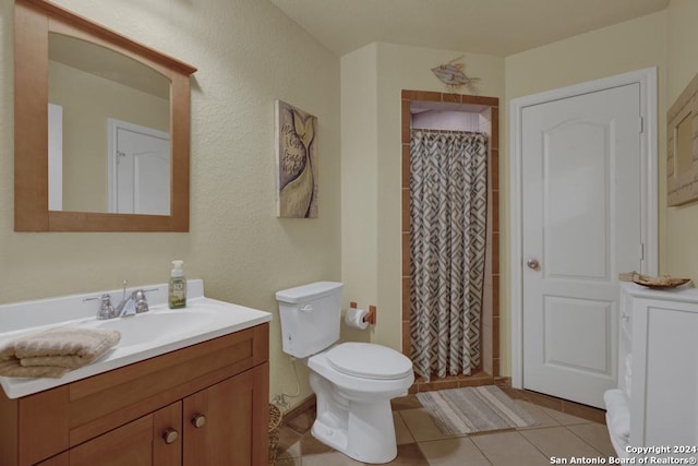 bathroom with tile patterned flooring, vanity, toilet, and walk in shower