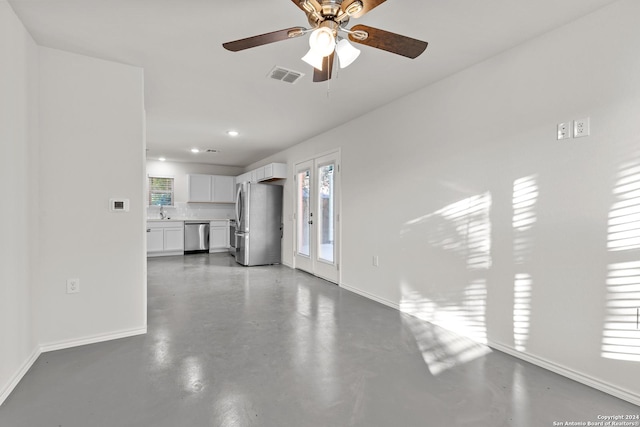 unfurnished living room featuring ceiling fan, sink, and concrete floors