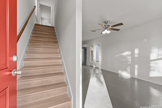 staircase featuring ceiling fan and concrete flooring